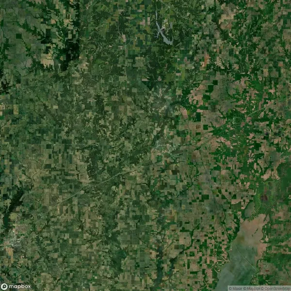 Aerial view of a green and brown patchwork landscape, showing fields, forests, and scattered small bodies of water.