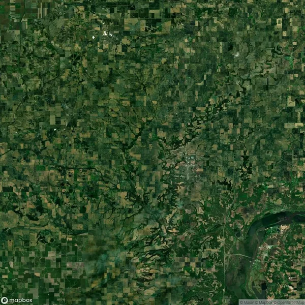 Aerial view of a vast, green, patchwork farmland landscape with a river visible in the bottom right corner.