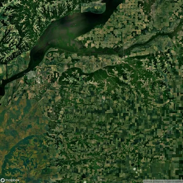 Aerial view of a patchwork landscape with fields, rivers, and forests. The top area shows a large river with surrounding greenery and farmland patterns in various shades of green.