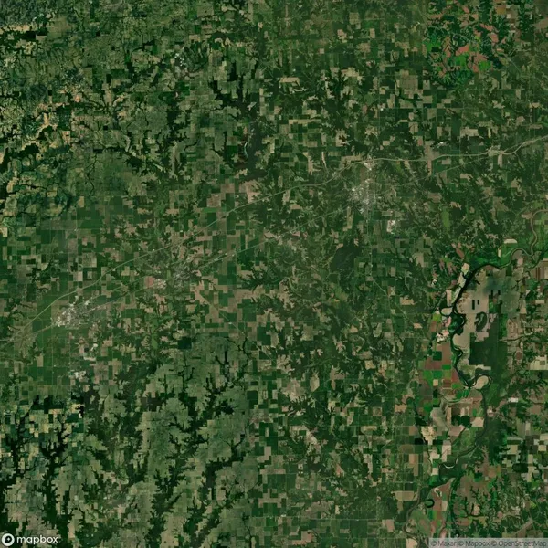 Satellite image showing a vast, green, patchwork landscape with fields, forests, and a winding river on the right.