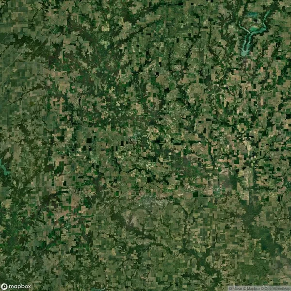 Satellite view of a patchwork of agricultural fields and forested areas, with a winding river in the top right section.