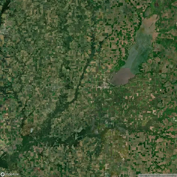 Satellite image of a rural landscape with agricultural fields, a river running through it, and a large body of water in the upper right corner.