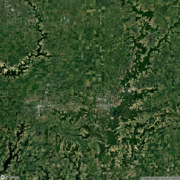 Aerial view of a rural landscape with patchwork fields, dense green forests, and scattered waterways.