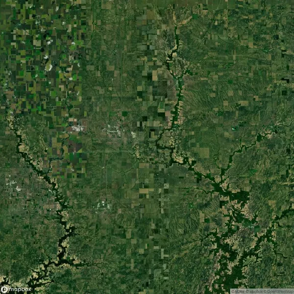 Aerial view of a green landscape with patchwork fields, roads, and winding rivers, surrounded by rural and forested areas.