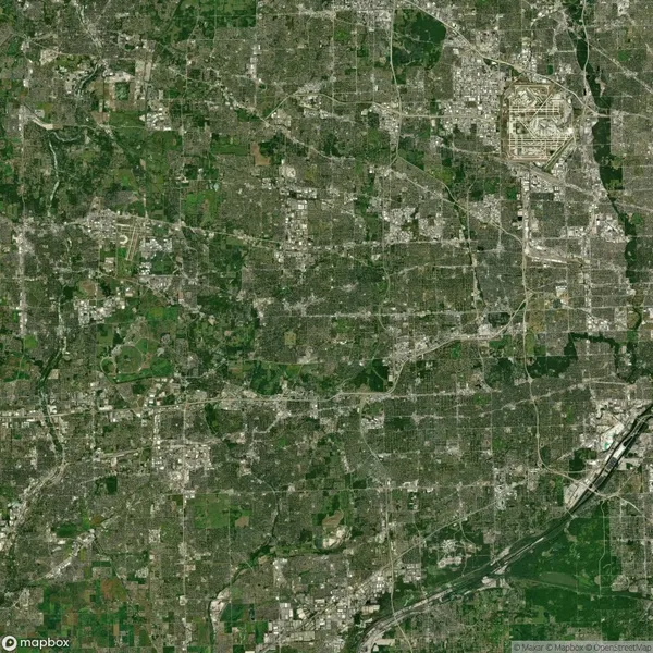 Satellite image of a sprawling urban area with a grid-like street pattern, featuring dense clusters of buildings and green spaces interspersed throughout.