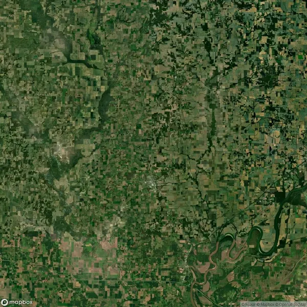 Aerial view of a vast, patchwork landscape with agricultural fields, scattered greenery, and a winding river near the bottom right corner.