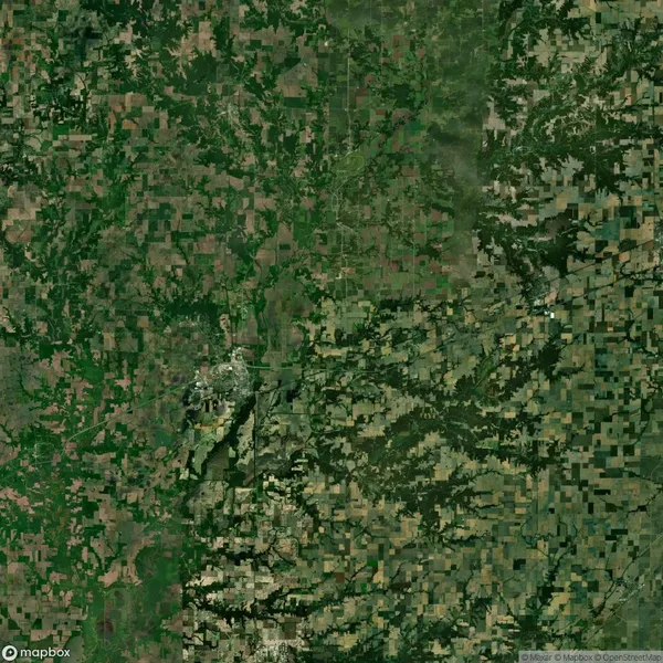 Aerial view of a vast landscape showing a patchwork of green and brown fields, roads, and small clusters of buildings.