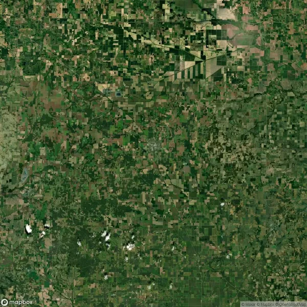 Aerial view of a vast green and brown patchwork landscape, showing farmland and fields, crisscrossed by roads and dotted with small white clouds.