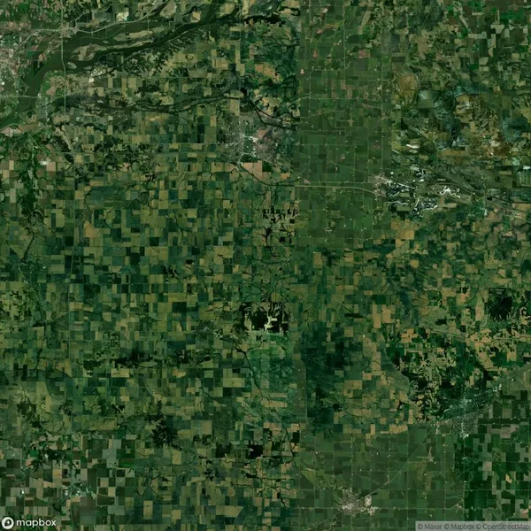 Aerial view of a patchwork landscape featuring agricultural fields and patches of greenery under a clear sky.