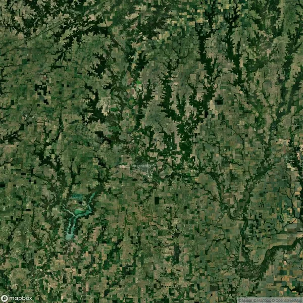 Aerial view of a landscape featuring a patchwork of agricultural fields and forested areas, with a river running through the lower left section.