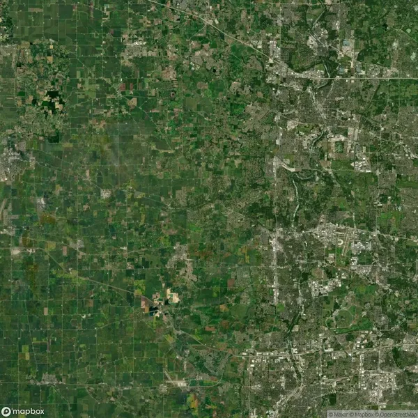 Satellite view of a sprawling urban and rural landscape with a clear demarcation between densely populated areas on the right and agricultural fields on the left.
