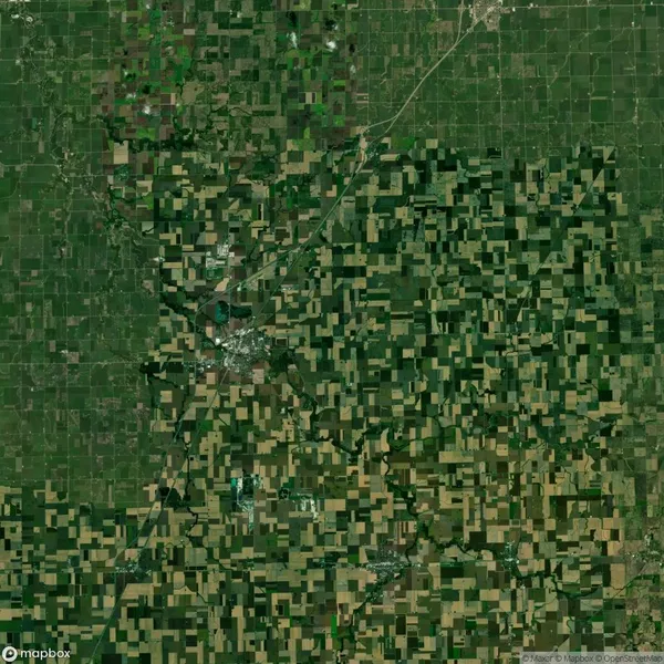 Aerial view of a widespread patchwork of agricultural fields and rural roads, with a small town located centrally in the landscape.