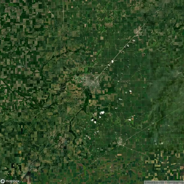 Aerial view of Lincoln, Nebraska, showing a grid pattern of agricultural fields and a dense urban area at the center. Sparse clouds are scattered across the sky.