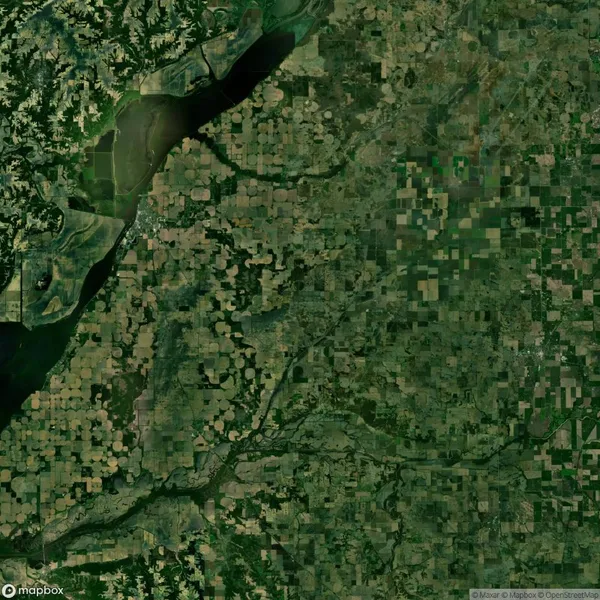 Aerial view of a patchwork landscape with diverse green and brown agricultural fields and a river flowing in the upper left corner.