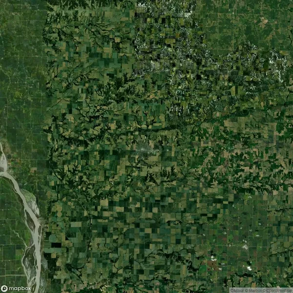 Aerial view of a large, green agricultural landscape with patchwork fields and a winding river on the left side.