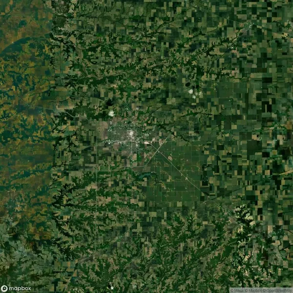 Satellite view of a rural landscape with a grid pattern of agricultural fields and a central urban area surrounded by greenery.