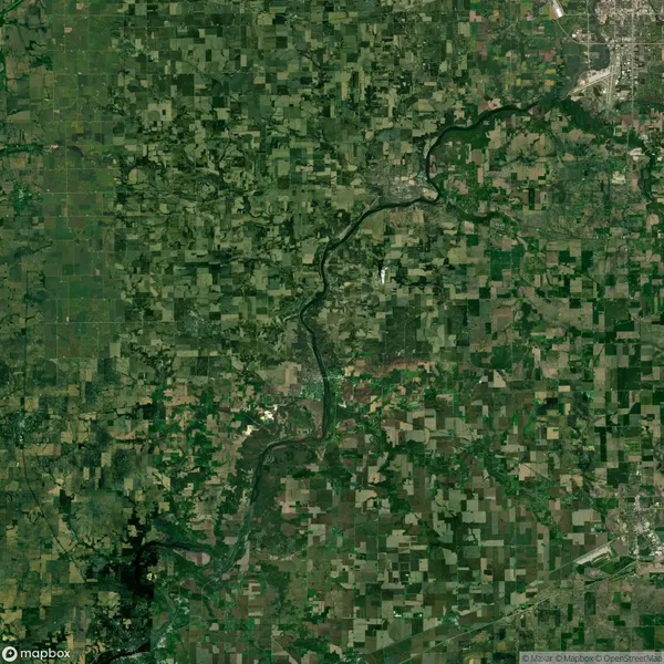 Aerial view of a river winding through a patchwork of farmland and green fields with a few urban areas visible.
