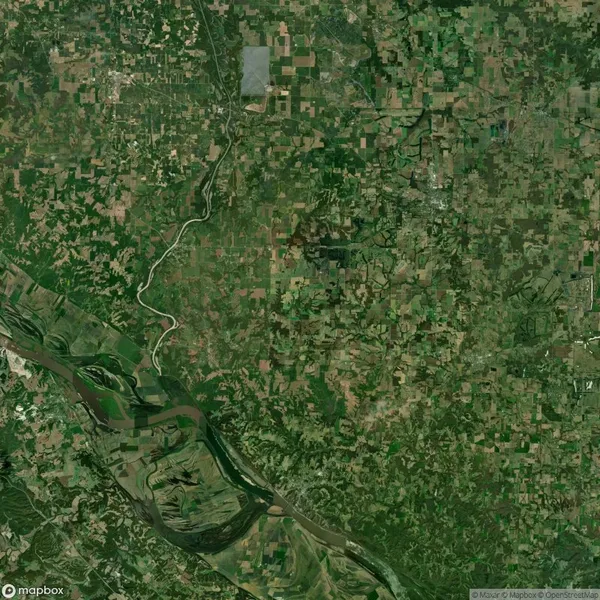 Aerial view of a rural landscape with patchwork farmland, forests, and a winding river in the lower left corner.