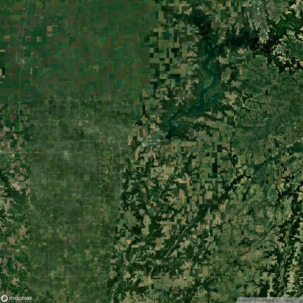 Satellite view of a landscape with a mix of agricultural fields and a winding river or reservoir. The area on the left appears flatter and more grid-like compared to the right.
