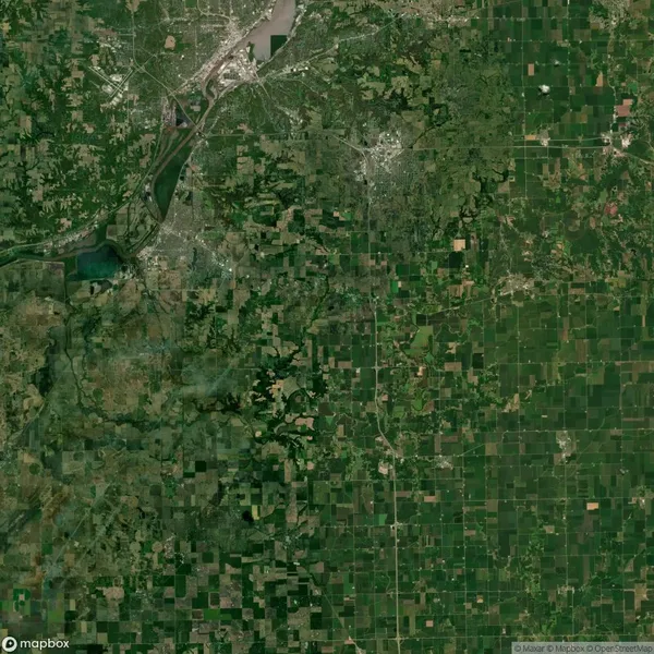 Satellite image of a geographical region showing a mosaic of agricultural fields, roads, and urban areas interspersed with green patches.