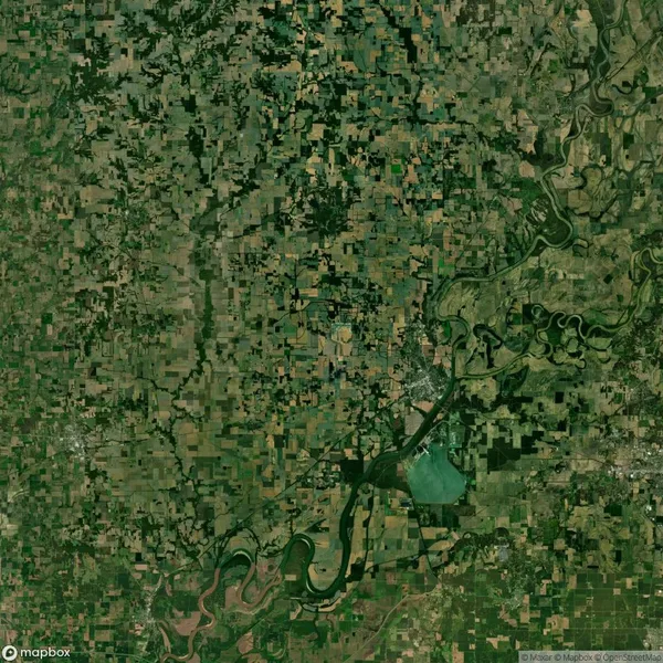 Aerial view of a green agricultural landscape with large river running diagonally. Fields appear in various shades of green and brown, indicating different stages of cultivation and land use.