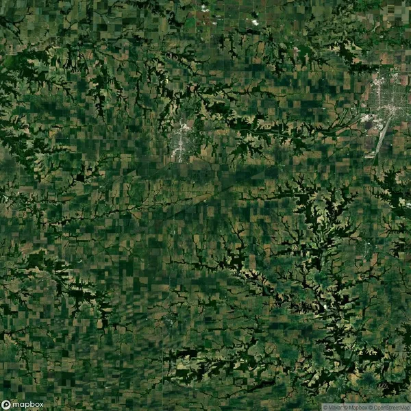 Aerial view of patchwork farmland and greenery, with roads and small clusters of buildings throughout the landscape.