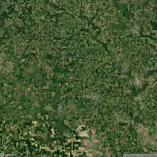 Aerial view of a vast rural landscape with densely packed green and brown patches indicating farmland and forested areas.