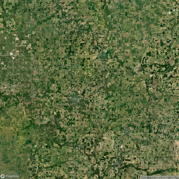 Aerial view of a patchwork landscape with green and brown agricultural fields, intersected by roads and a winding river, under clear weather.