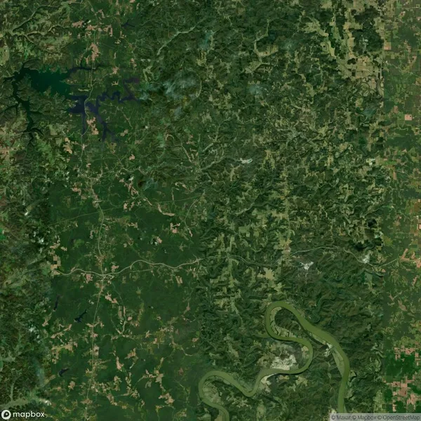 Aerial view of a lush green landscape with winding roads, dense forest, and a river snaking through the terrain.