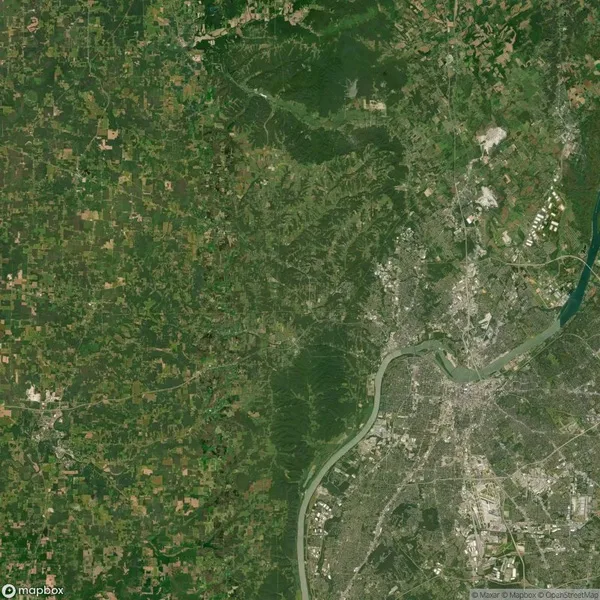 Aerial view of a landscape showing a dense urban area on the right, a winding river, and a large expanse of green fields and forests on the left.
