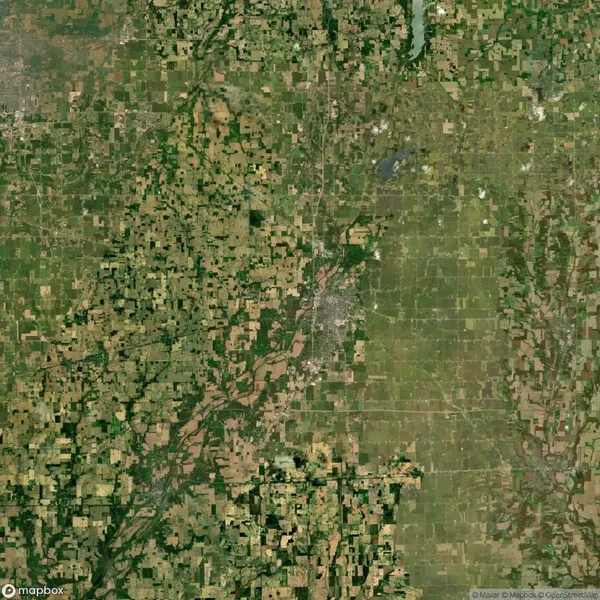 Aerial view of a sprawling, gridded agricultural landscape with a river running through it and a concentrated urban area in the center.