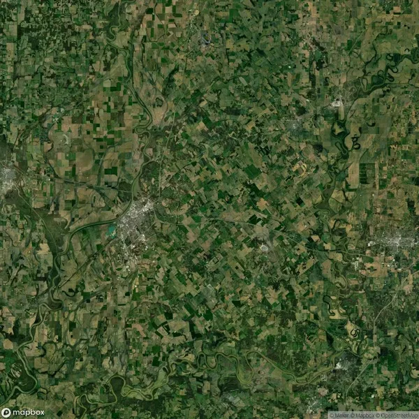 Aerial view of a rural landscape featuring farmland with fields, forests, and winding rivers spread across the area.