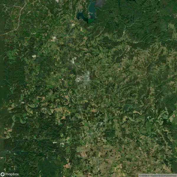 Aerial view of a landscape featuring a mix of green forests, winding rivers, and urban areas centered around a dense city.