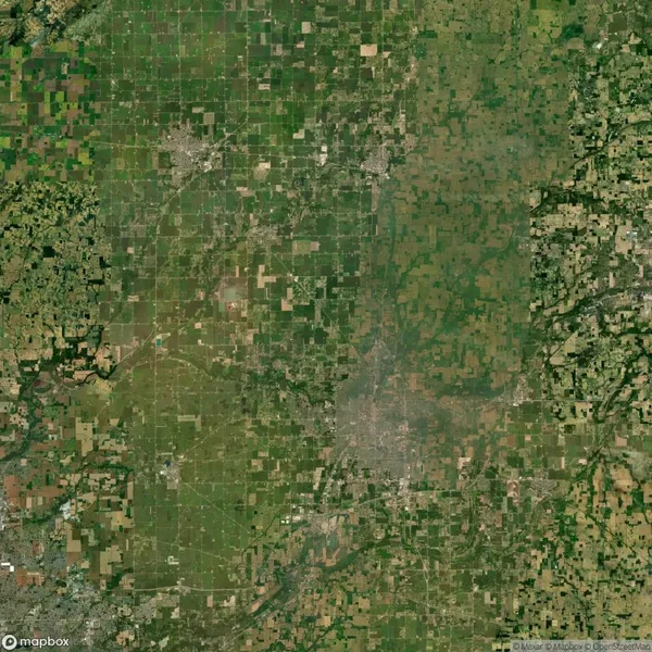 Aerial view of a sprawling landscape with a grid-like pattern of agricultural fields and small urban areas interspersed with patches of greenery.