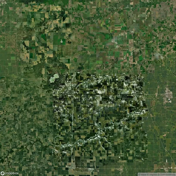 Aerial view of a patchwork landscape featuring a river winding through agricultural fields and green patches, creating a mosaic pattern.