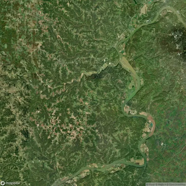 Aerial view of a large, winding river flowing through a green, forested landscape with scattered patches of farmland.
