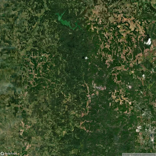 Aerial view of a vast landscape with a patchwork of green forests and brown farmland. A winding river runs through the center.