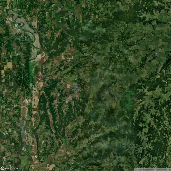 Aerial view of a large green landscape with a mix of agricultural fields, forests, and a river running through the left side of the image.