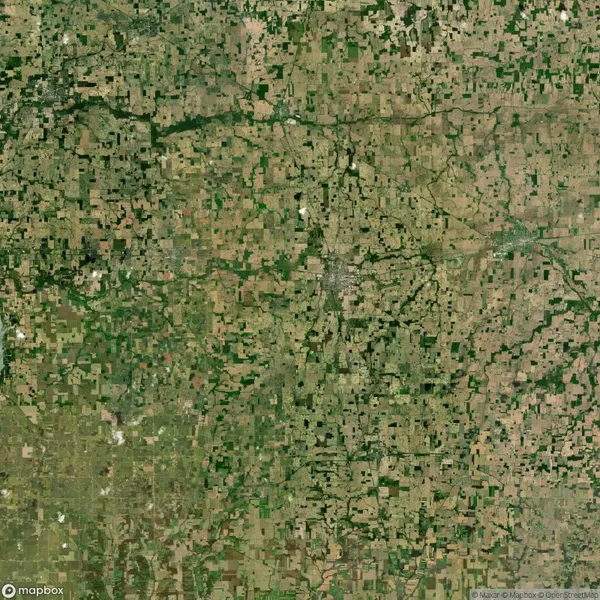 Aerial view of a patchwork landscape with a mix of green and brown agricultural fields and scattered small urban areas.