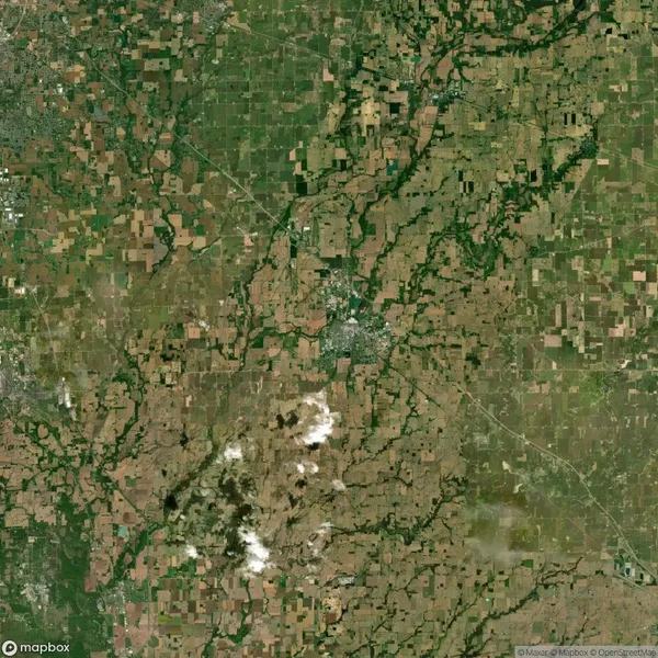 Aerial view of a rural landscape featuring patchwork fields, scattered trees, and small clusters of buildings, intersected by roads.