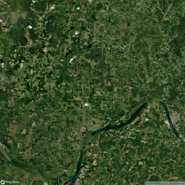 Aerial view of a rural landscape with green patches of farmland, a winding river, and scattered clouds.