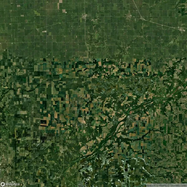 Aerial view of a rural landscape with a grid-like pattern, showing a mix of farmland, roads, and green vegetation.