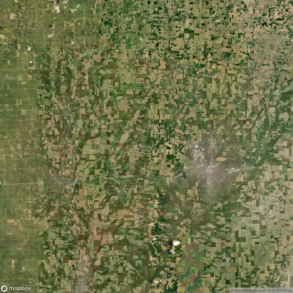 Aerial view of a patchwork landscape with agricultural fields and a small urban area on the right.
