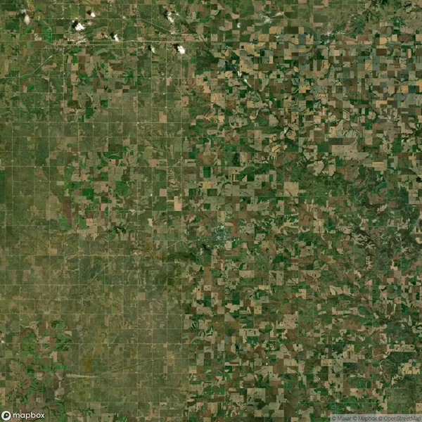 Aerial view of a rural landscape featuring a patchwork of green and brown agricultural fields arranged in a grid pattern.