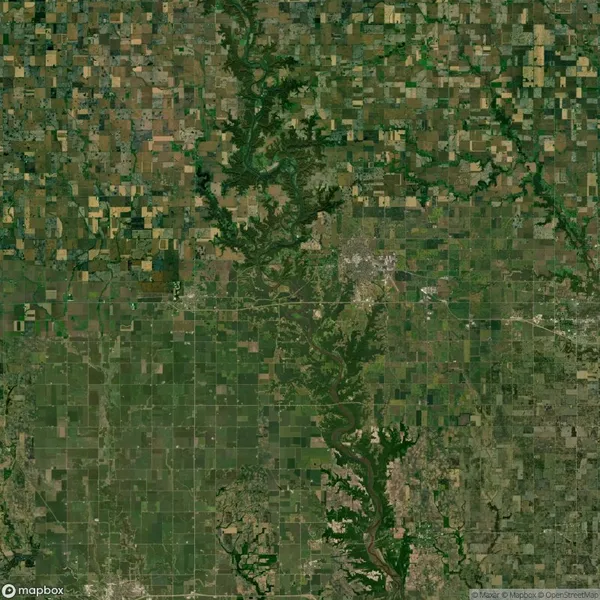 Satellite view of a landscape featuring a patchwork of agricultural fields, with green vegetation and winding river. Urban areas are visible at the center right.