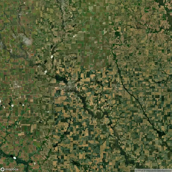 Aerial view of a patchwork landscape with a mix of farmland and green areas separated by irregular patterns of trees and small waterways.