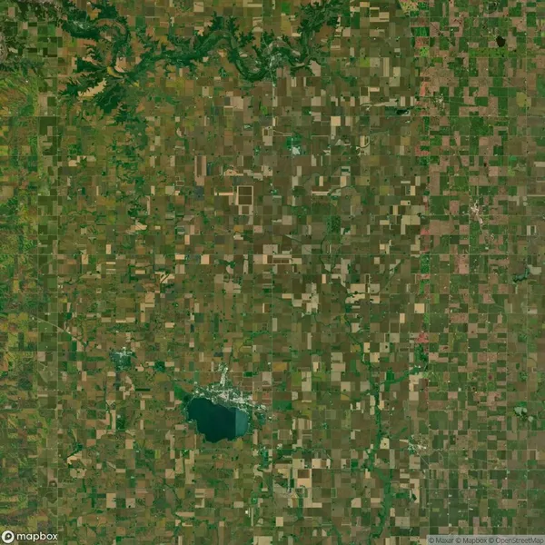Aerial view of a rural landscape with a patchwork of agricultural fields, a river at the top, and a lake near a small town at the bottom.