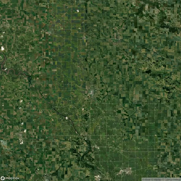 Aerial view of a landscape featuring a patchwork of agricultural fields, a meandering river on the left, and small clusters of trees and vegetation.