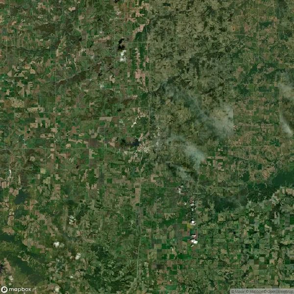Aerial view of a large area showing a patchwork of green and brown agricultural fields with scattered cloud cover.