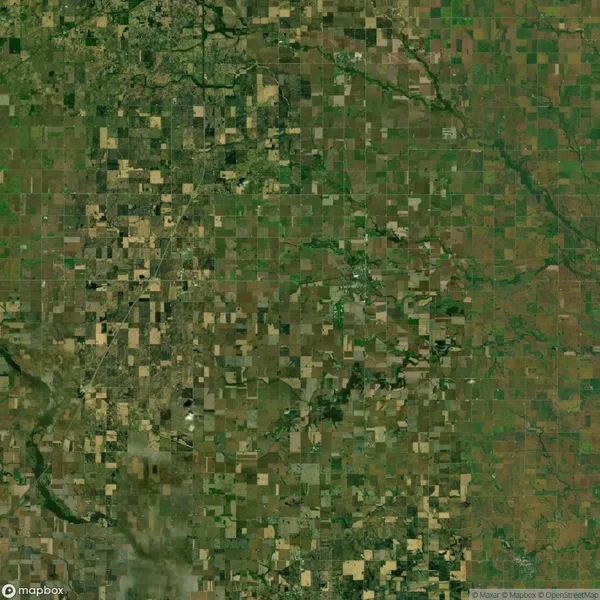 Aerial view of a patchwork landscape with green and brown agricultural fields intersected by roads and rivers.